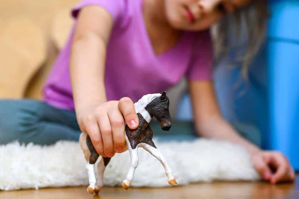 Mädchen spielt mit einem kleinen Pferd
