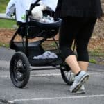 junge Frau schiebt Kinderwagen beim Joggen
