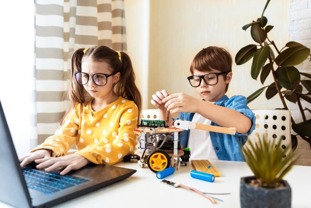 Kinder basteln mit einem Roboter und dem Laptop