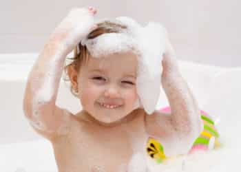 Baby spielt mit Schaum in der Badewanne