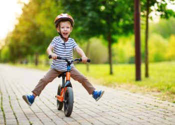 fröhlicher Junge auf einem Balance Bike