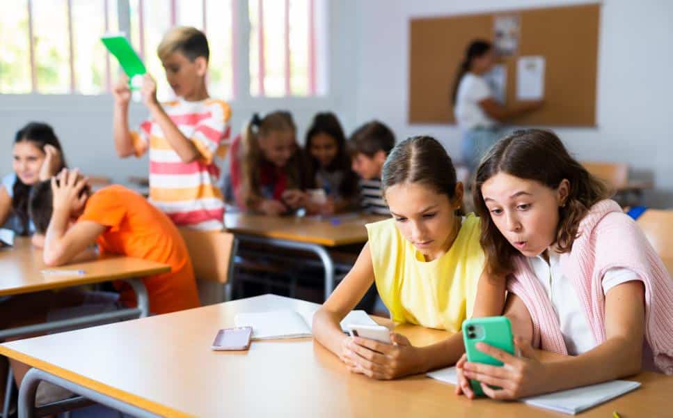 Kinder in der Schule mit Handys in der Hand